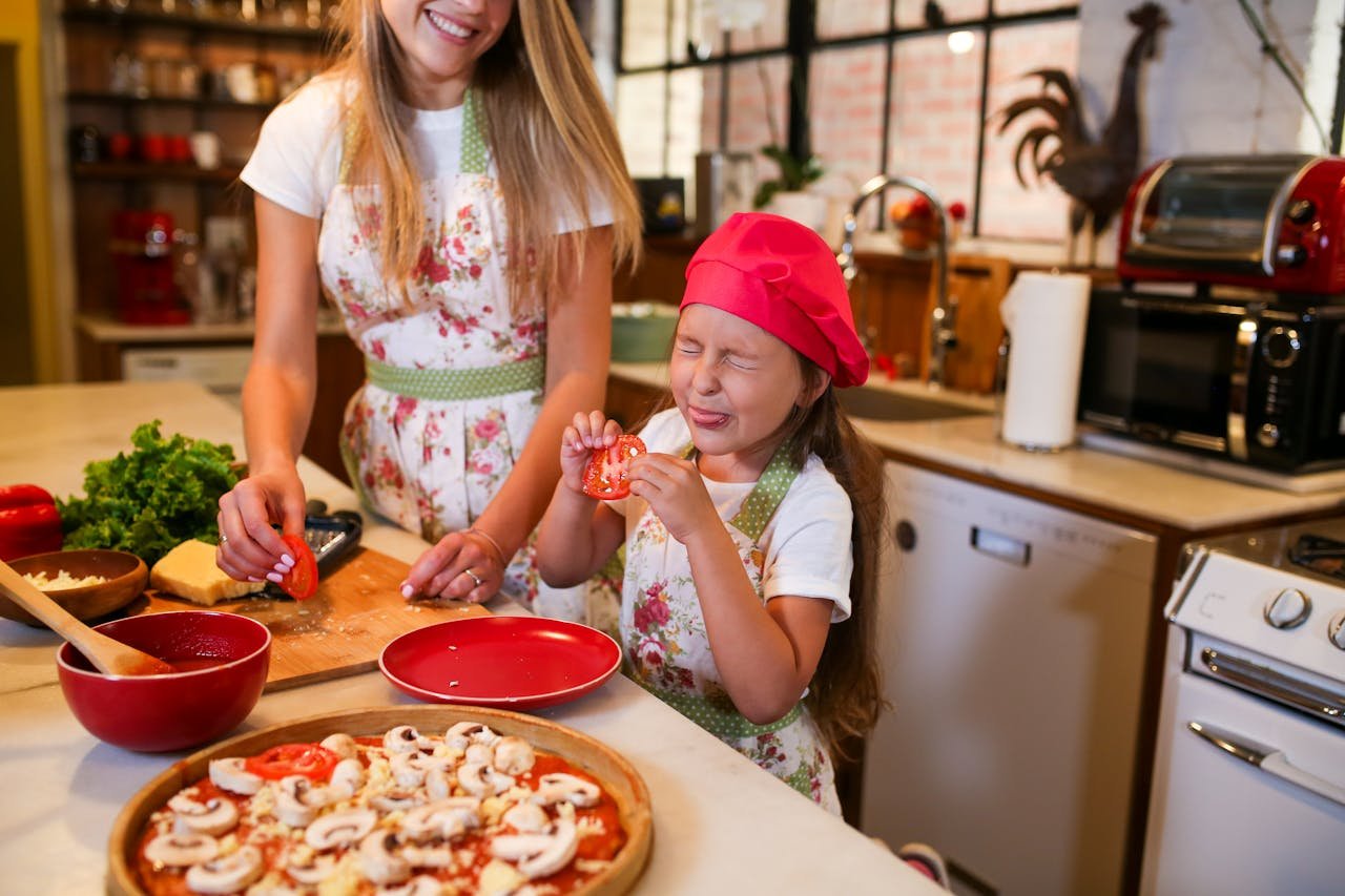 Happy mother and daughter making pizza together in a home kitchen, sharing quality family time.